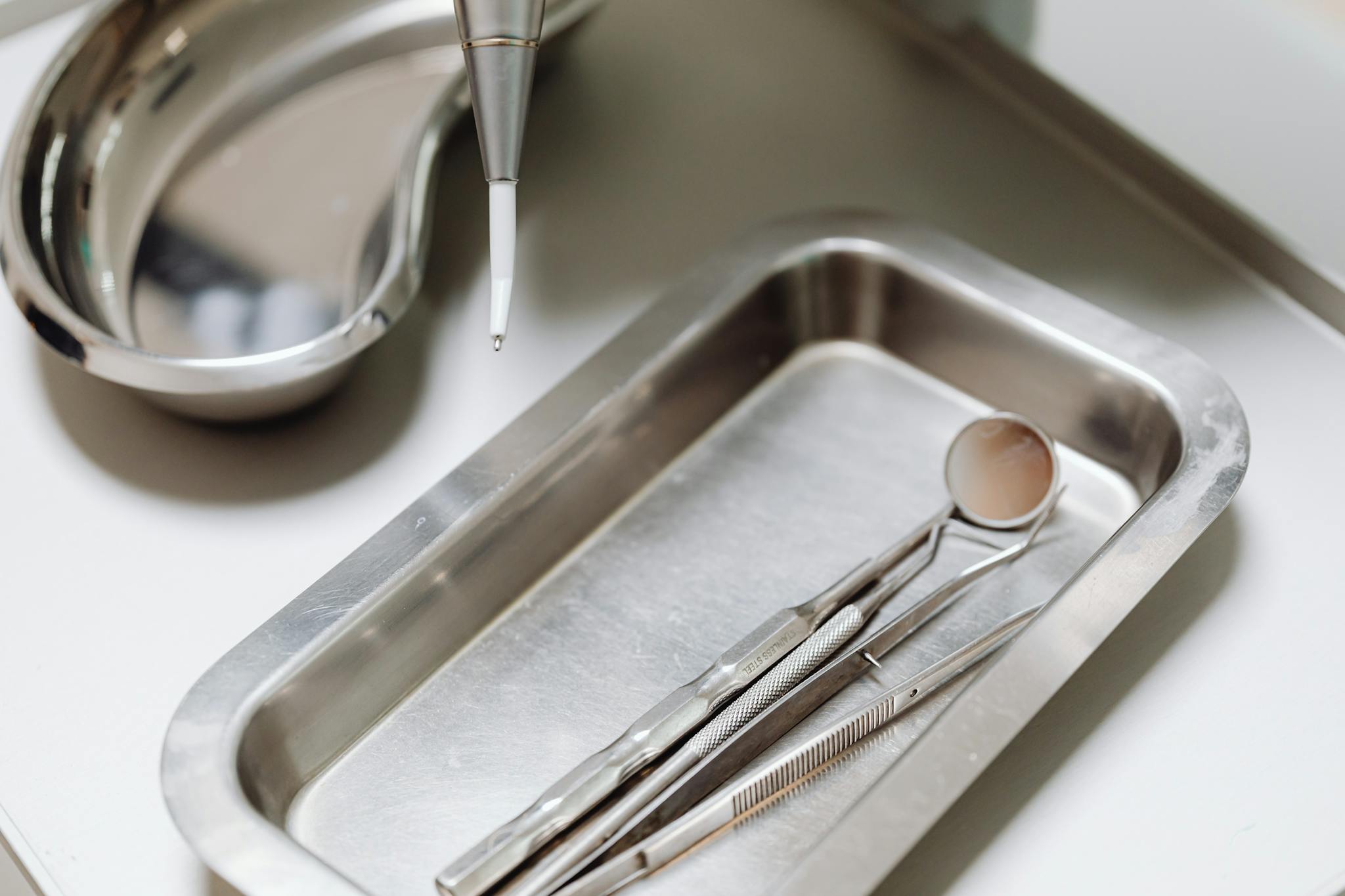Close-up of dental tools on a clean, sterile metal tray, emphasizing hygiene and precision.