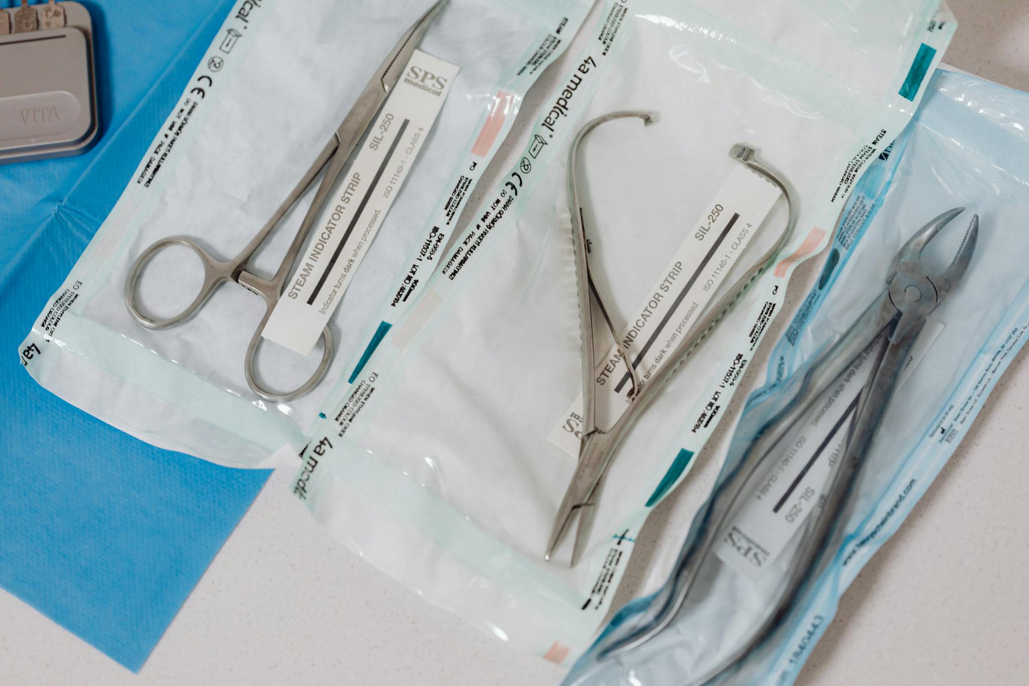 Close-up of sterilized surgical tools in packaging on a clinical table.