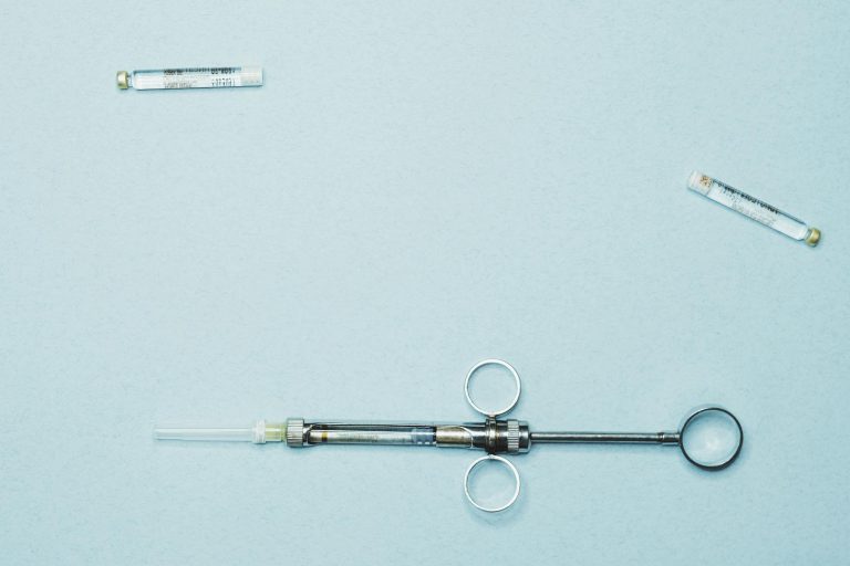 High-quality stock photo of a dental syringe and vials on a blue background. Ideal for dentistry.