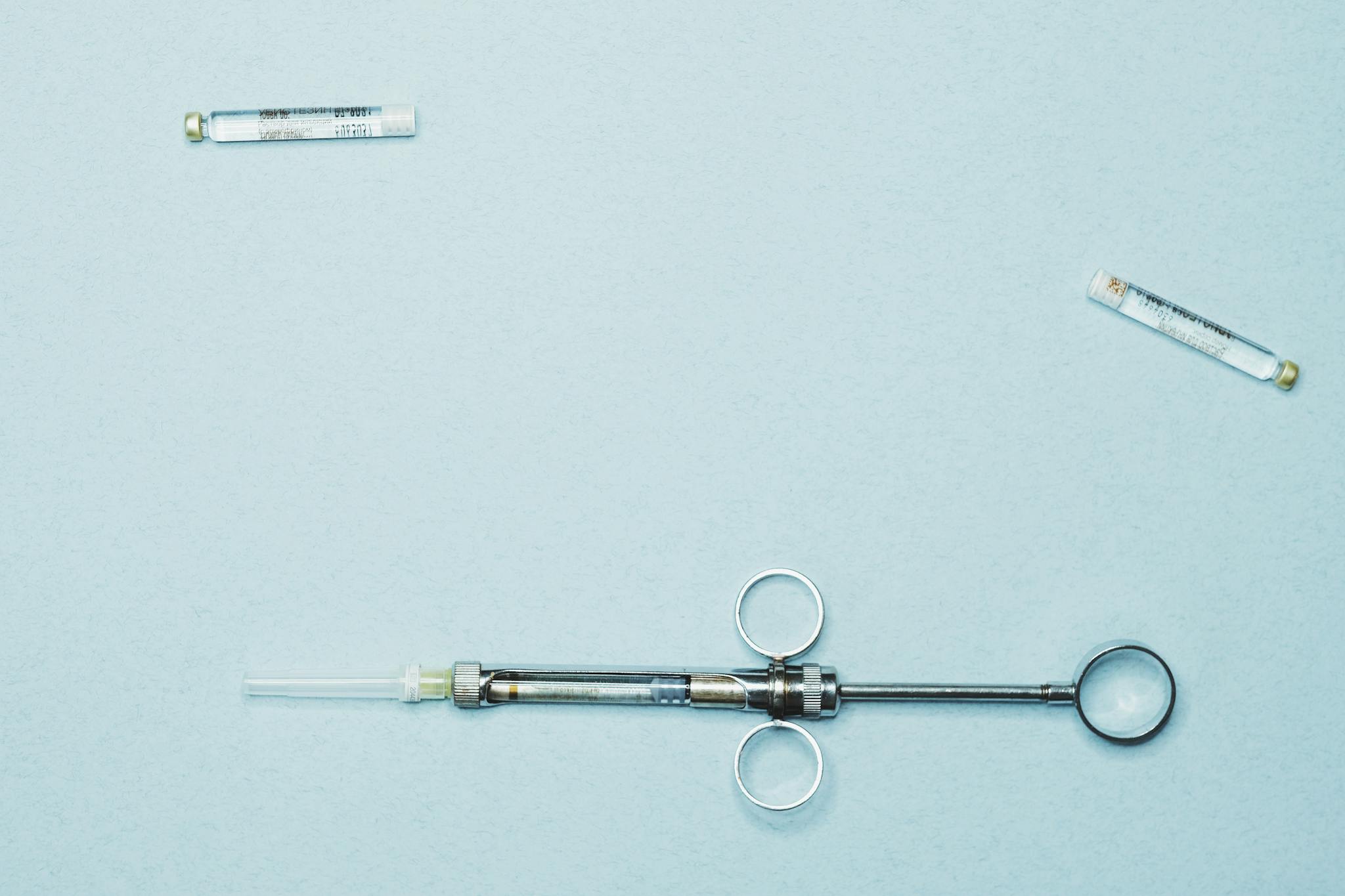 High-quality stock photo of a dental syringe and vials on a blue background. Ideal for dentistry.